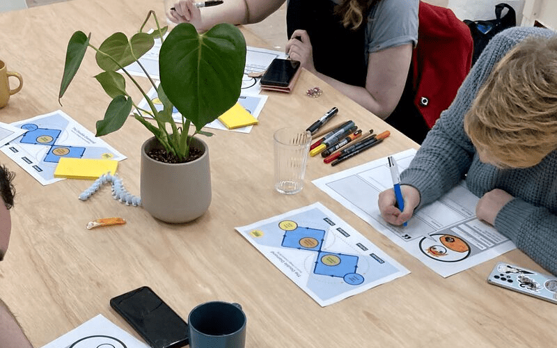 People drawing at a table with a green houseplant and printed Double Diamond diagrams.